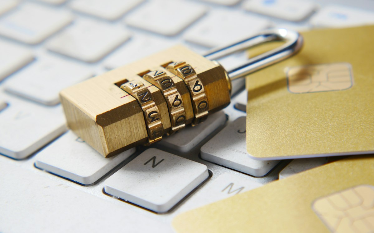 Gembok kombinasi emas di atas keyboard laptop di samping kartu bank