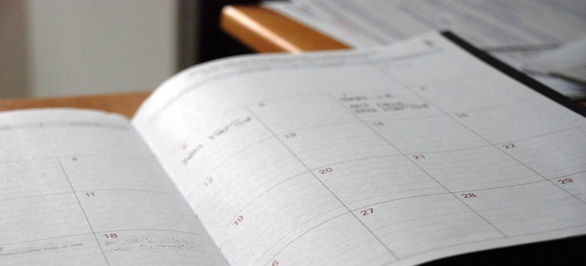 Planner bulanan terbuka di atas meja kayu