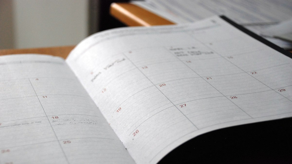 Planner bulanan terbuka di atas meja kayu