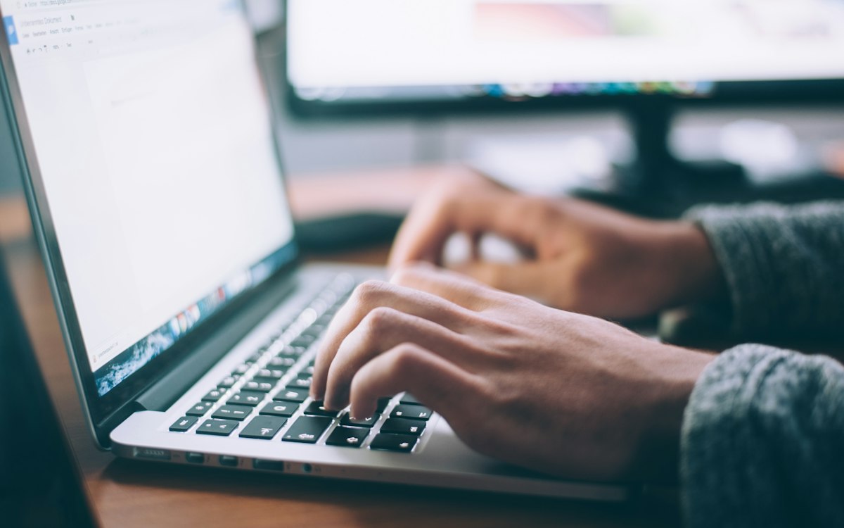 Một người đang dùng laptop trên bàn làm việc