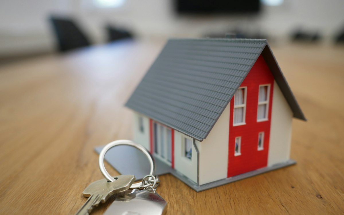 Miniatur rumah kayu kecil berwarna putih dan merah di atas meja
